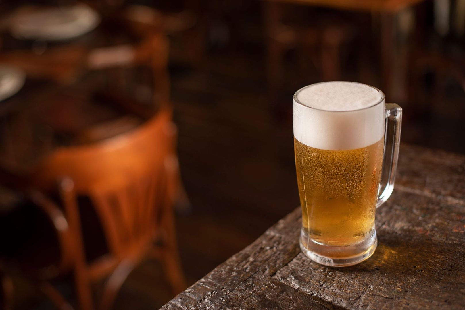 Fresh amber ale with a thick white head on a wooden bar