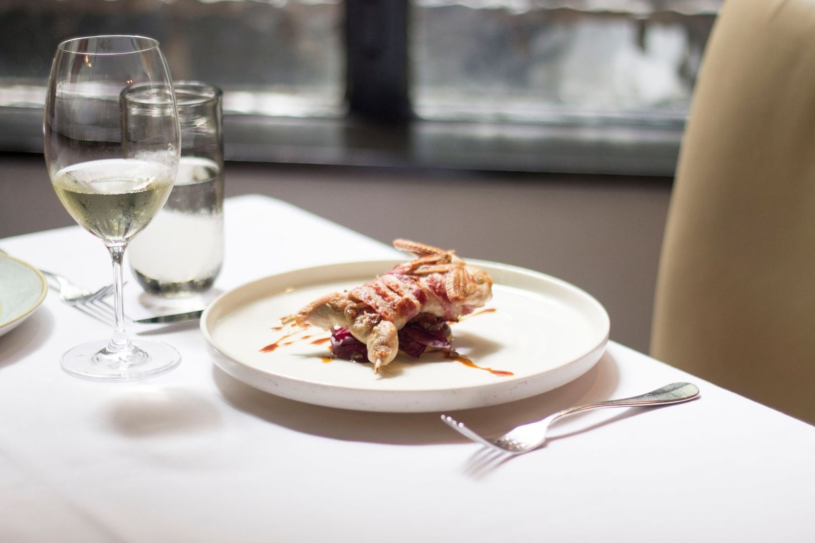 Roasted game bird served with white wine at a restaurant table
